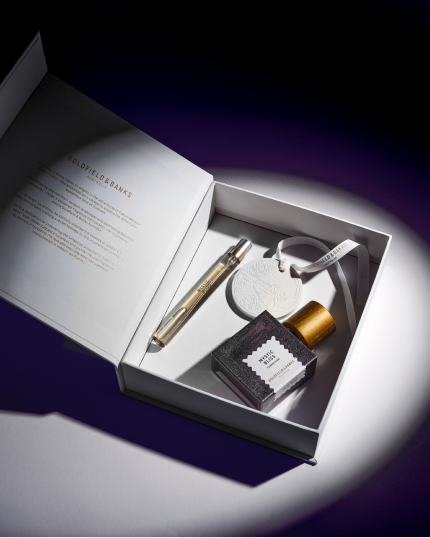 Goldfield & Banks luxury perfume gift set in a white box with full-size bottle, travel spray, and accessories under soft spotlight lighting.