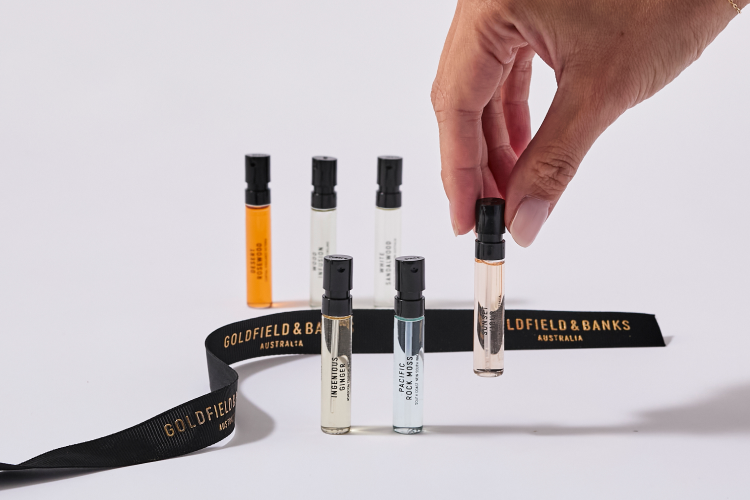 Hand holding Goldfield & Banks perfume samples with luxury fragrance discovery set on white background