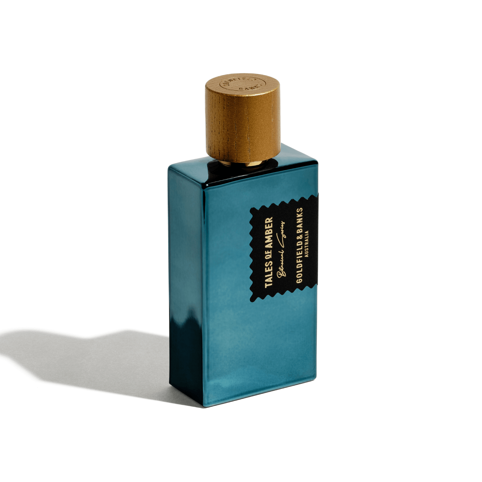 Blue rectangular 'Tales of Amber' perfume bottle with wooden cap and black label.